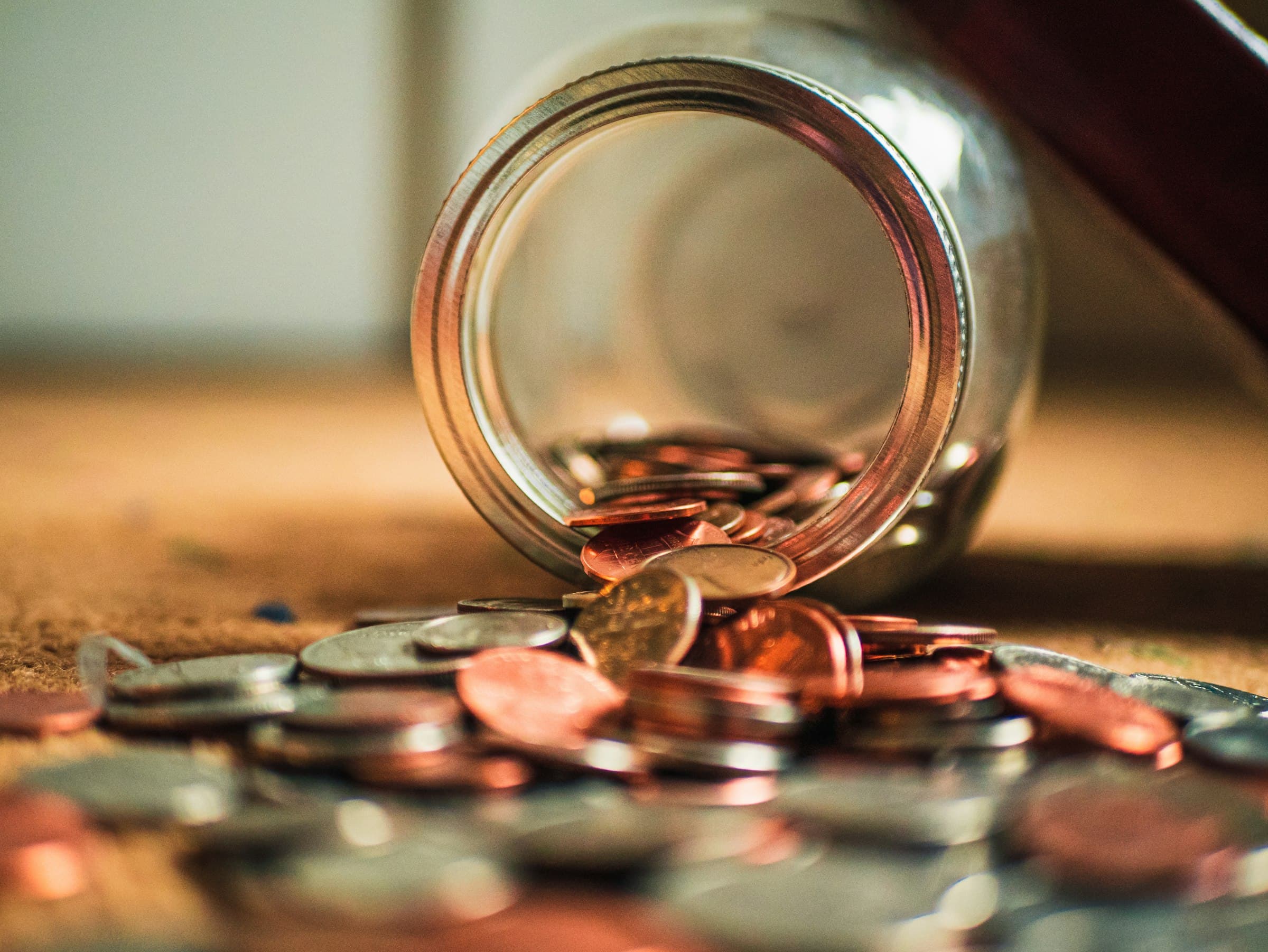 Coins spilling out of a tipped-over glass jar